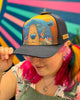 Person wearing a colorful cap with a bear design against a multicolored background