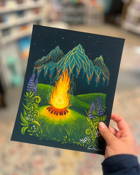 Single Paper print of a firepit in the summer of Alaska. the print is un framed and being held in Amandas Art Studio