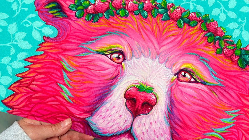Paper Print being held at an angle with bear dressed with a strawberry crown and a nose that looks like a strawberry