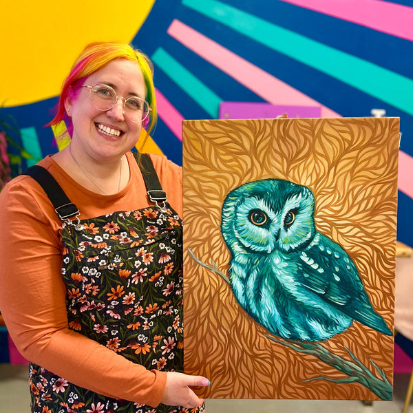 Person holding a painting of an owl in front of a colorful abstract background