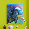 Colorful painting of a bison on a green wall with a lamp and decorative items below.