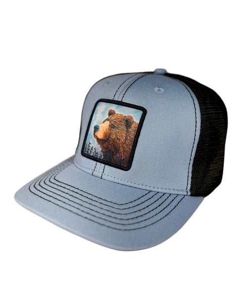 Bear On Guard ice blue trucker hat featuring Alaska brown bear design, adjustable mesh cap with bold wildlife-inspired artwork