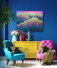 Colorful living room with a yellow console table, blue and pink armchairs, and a vibrant mountain painting on the wall.