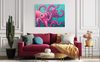 Living room with a pink couch, colorful octopus family painting, and decorative items.