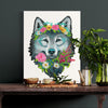 Art print of a wolf with floral crown on a table with decorative items.