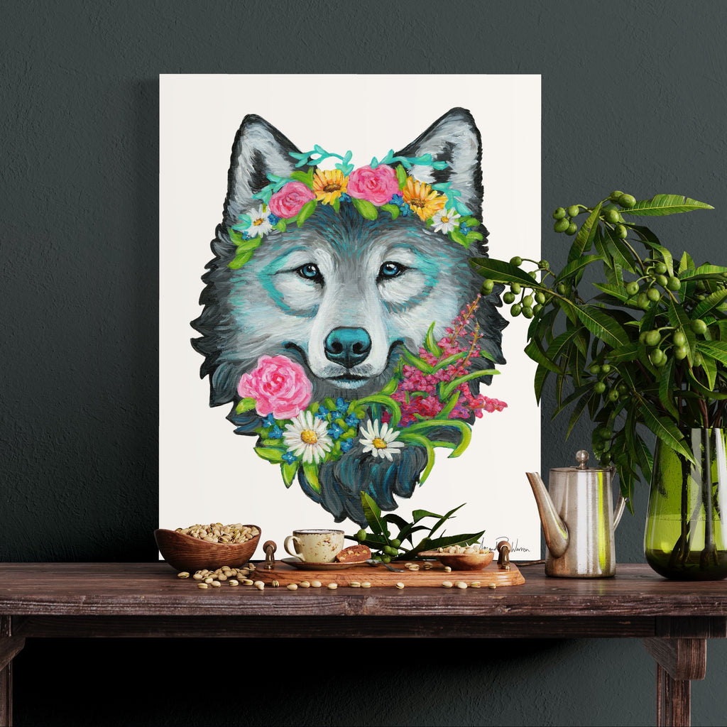 Art print of a wolf with floral crown on a table with decorative items.