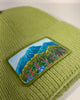 Green ribbed beanie with Alaska meadow floral design, showcasing fireweed and forget-me-not flowers in an artistic style