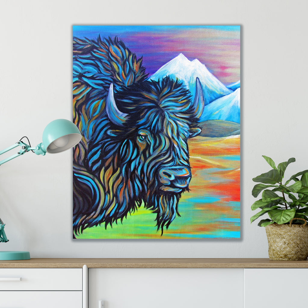 Colorful painting of a bison on a wall above a desk with a lamp and plant.