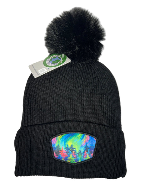 Mystic Trees fleece lined pom beanie featuring Alaska forest design with colorful rainbow trees, cozy winter knit hat