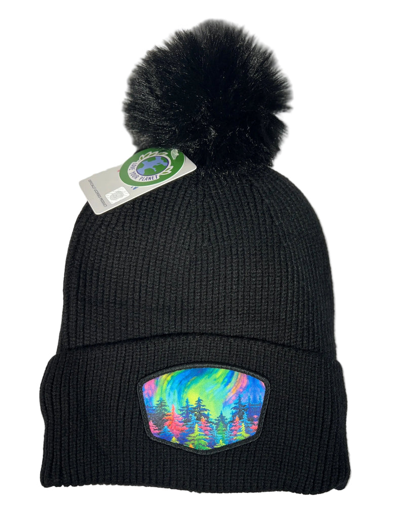 Mystic Trees fleece lined pom beanie featuring Alaska forest design with colorful rainbow trees, cozy winter knit hat