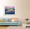 Framed colorful mountain landscape art in a living room with a light blue sofa and decorative pillows.