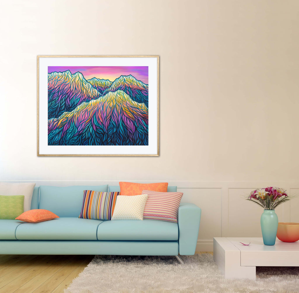 Framed colorful mountain landscape art in a living room with a light blue sofa and decorative pillows.