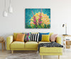 Living room with a yellow sofa, colorful pillows, and a vibrant blooming fireweed painting on the wall.