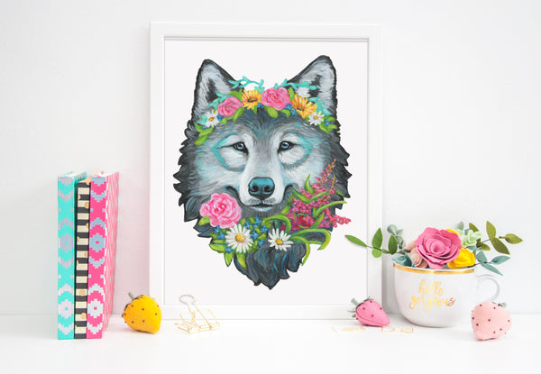 Framed artwork of a wolf with floral crown on a white surface with decorative items.