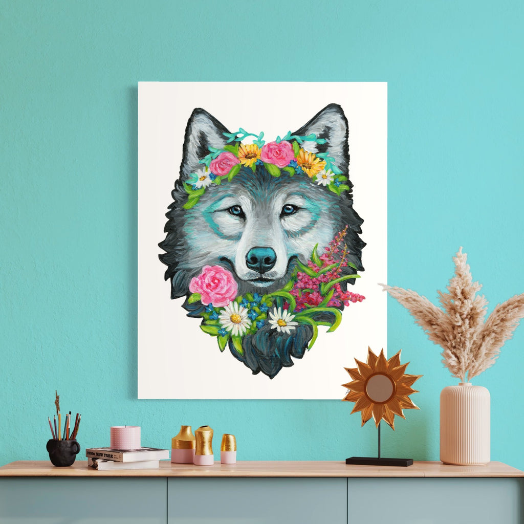 Fine art print of a wolf with floral crown on a teal wall above a wooden shelf.
