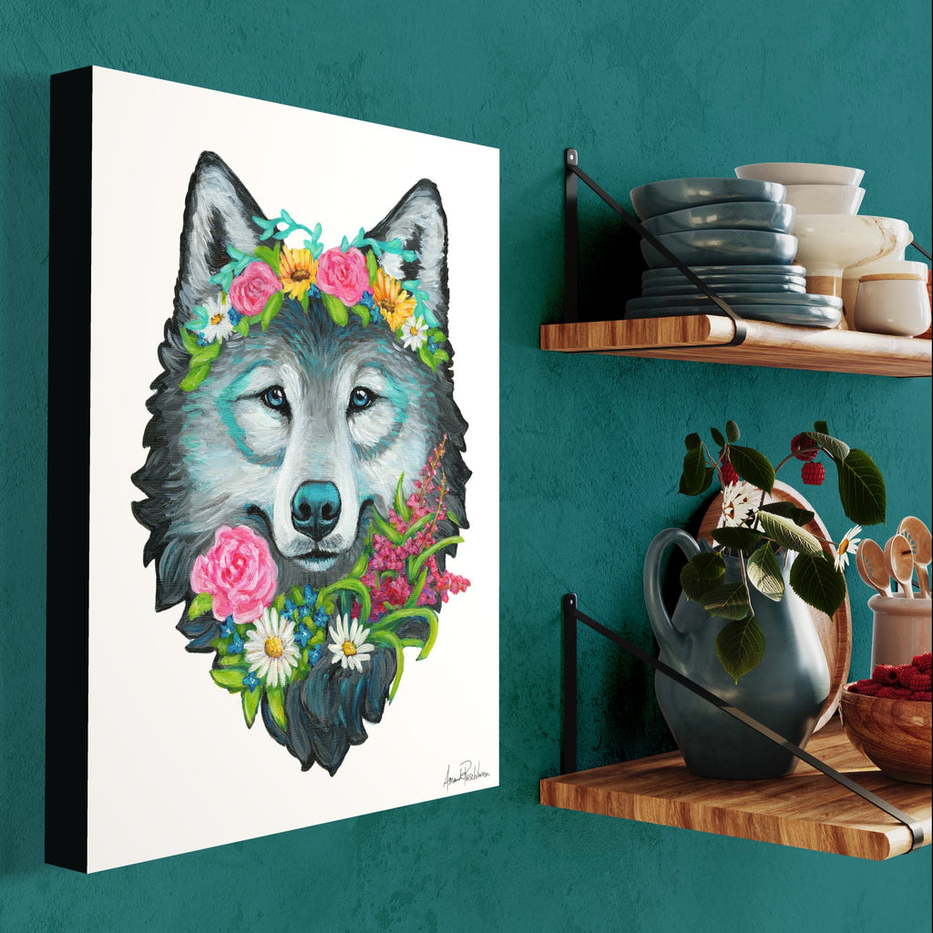 Canvas print of a wolf with floral decorations on a teal wall next to a wooden shelf.